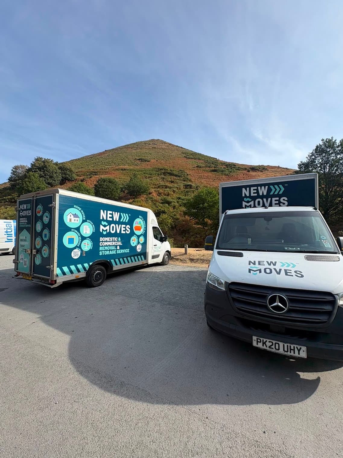 Two New Moves branded removal vans parked with a Shropshire hillside in the background
