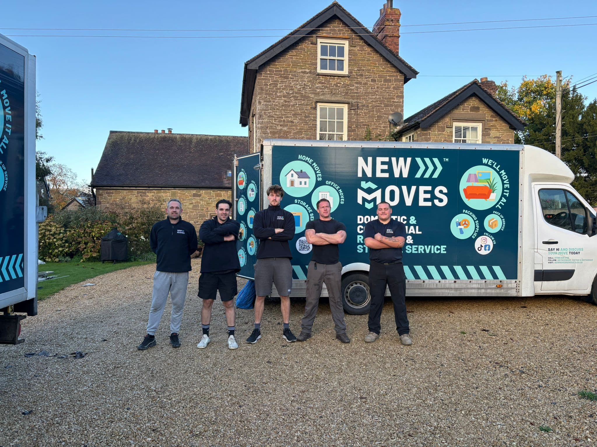 The New Moves Removals team standing in front of their branded removal van outside a period stone property