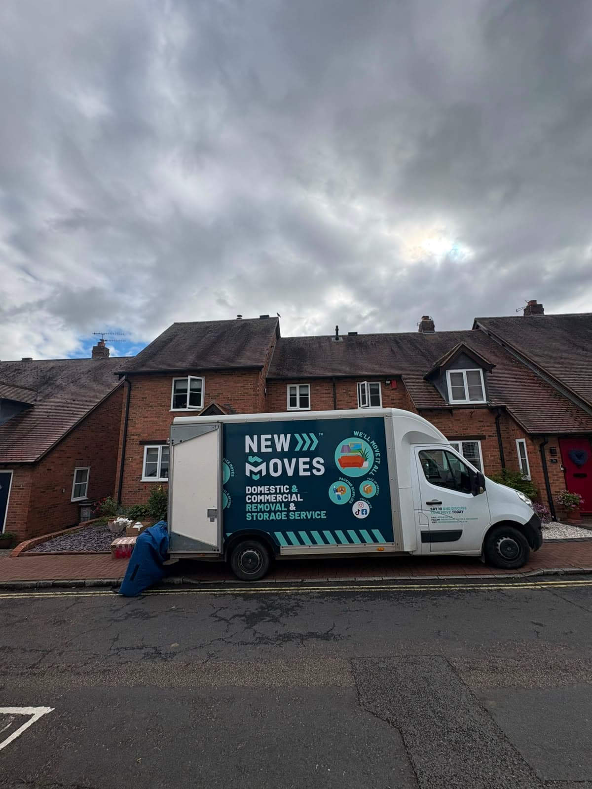 A New Moves Removals van parked on a residential street of brick terraced houses
