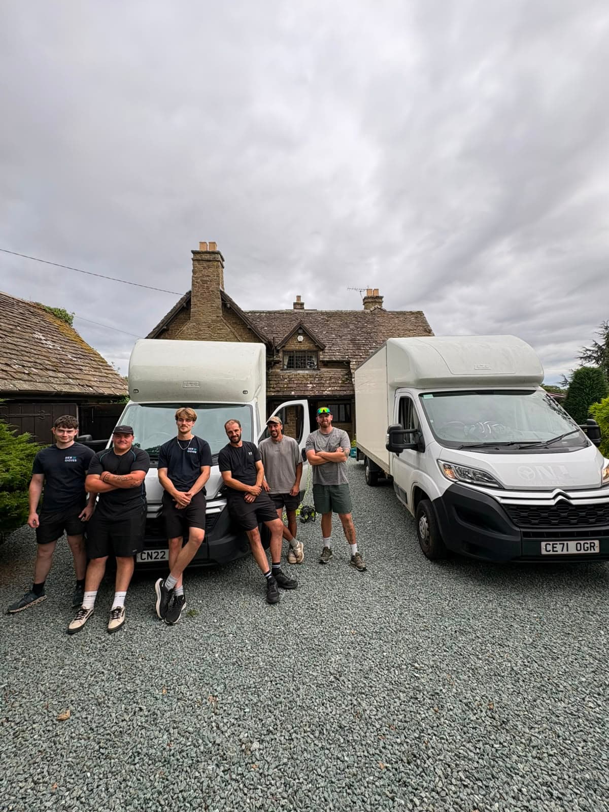 A New Moves Removals van parked outside a rural brick house behind a hedge