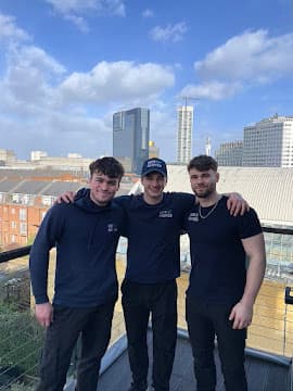 Three New Moves Removals team members outdoors, with a city skyline in the background