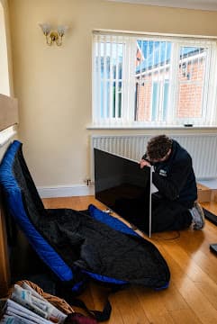 A New Moves Removals team member preparing a television in a protective padded case