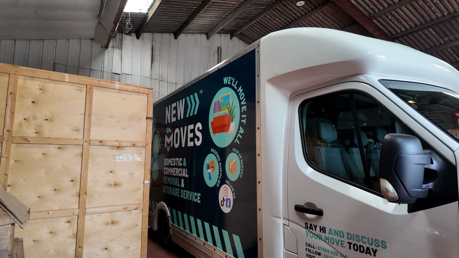 A New Moves Removals van parked inside a storage warehouse beside a large wooden storage crate
