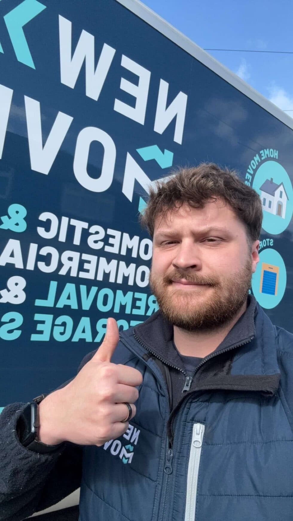 New Moves Removals Operations Manager taking a selfie in front of the branded removal van, giving a thumbs up