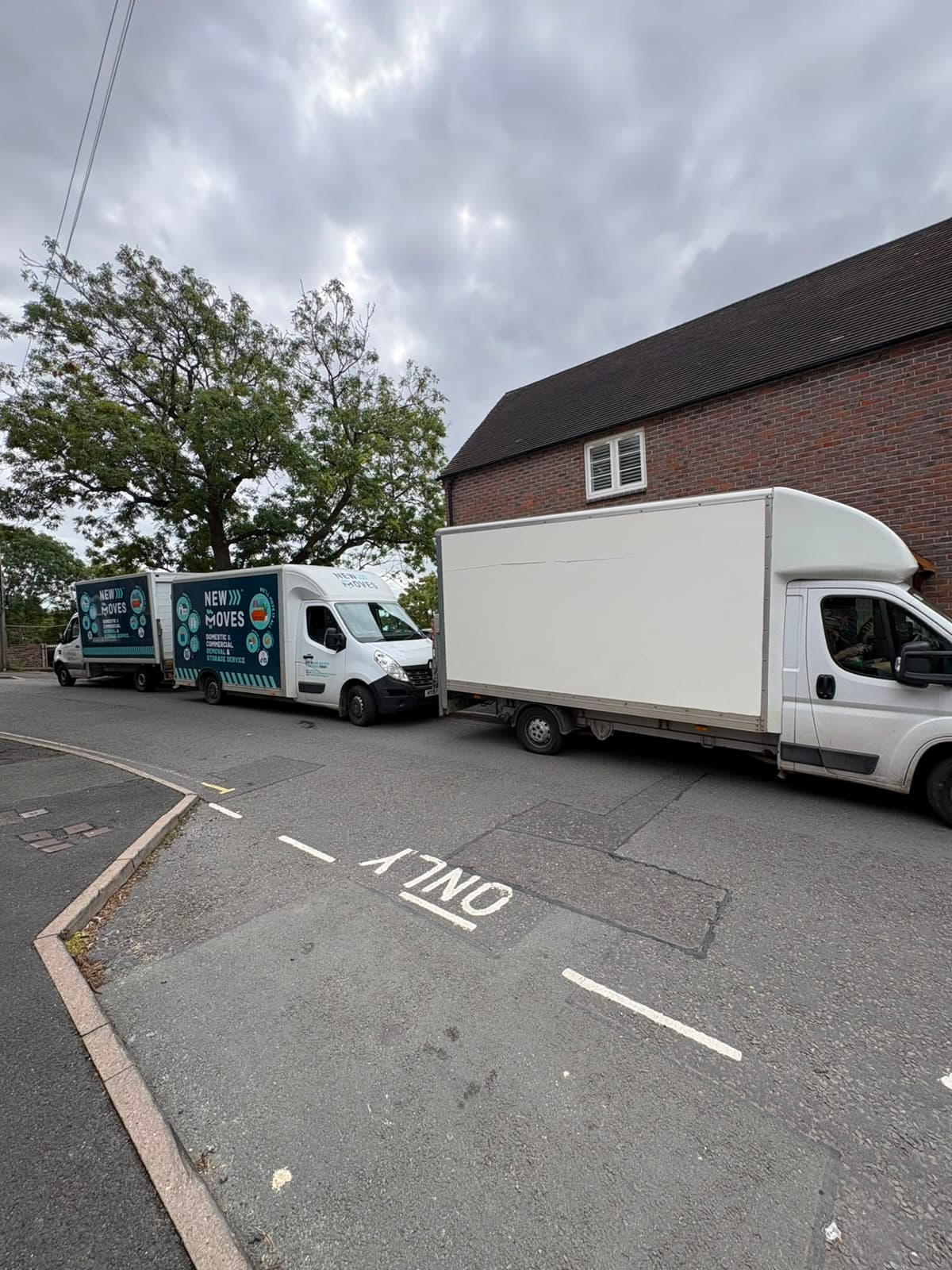 Two New Moves Removals vans parked nose to tail on a narrow residential street